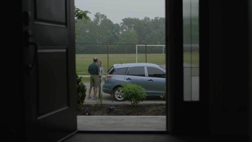 Two people hug by a car outside