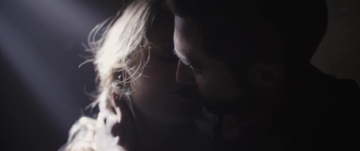 A man and woman kiss while their breaths fog