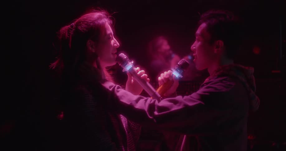 Two people sing into the microphones