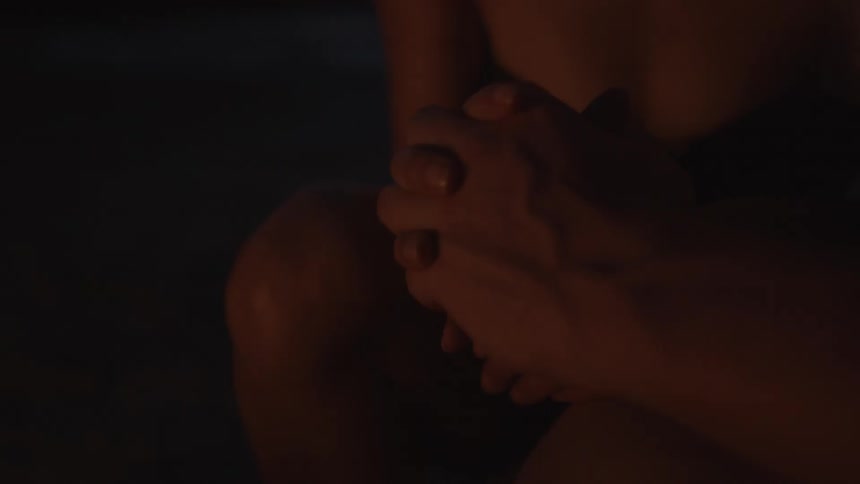 A man and woman hold hands next to a bonfire