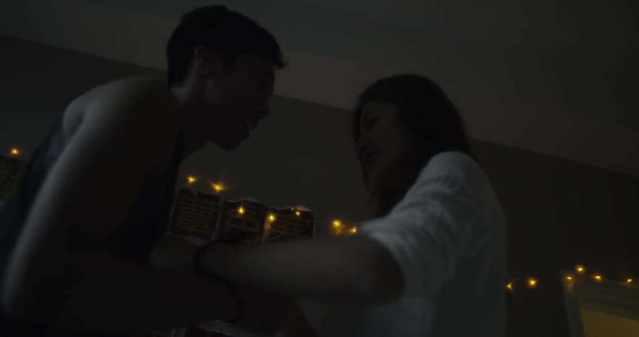 A man and woman are play fighting in a dark room