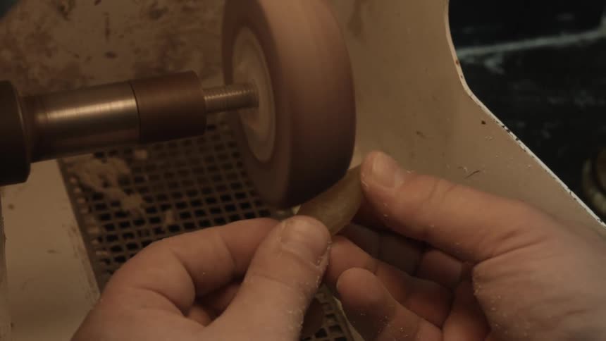 Person sands a gemstone on a wheel