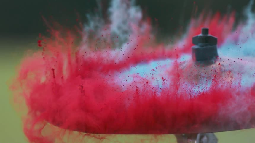 Drumstick hits a cymbal and red powder flies off of it
