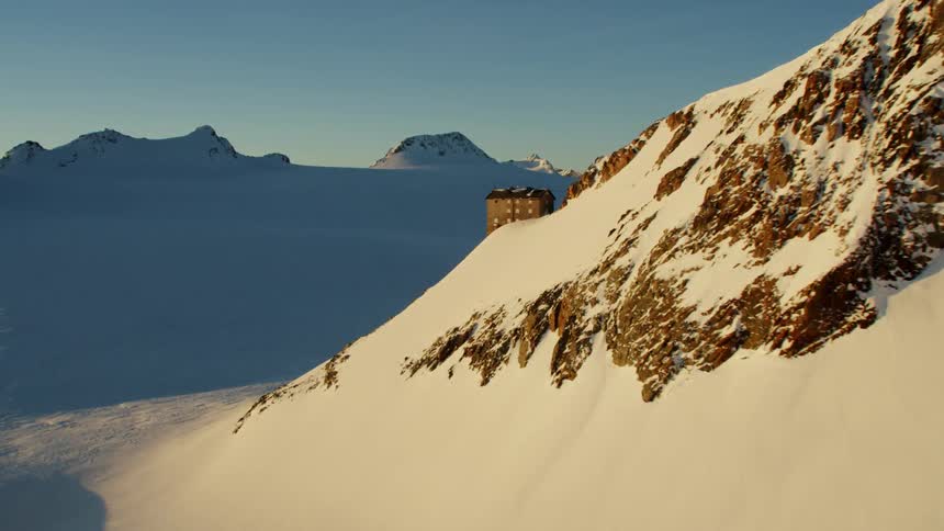 A building on the edge of a snow covered mountain