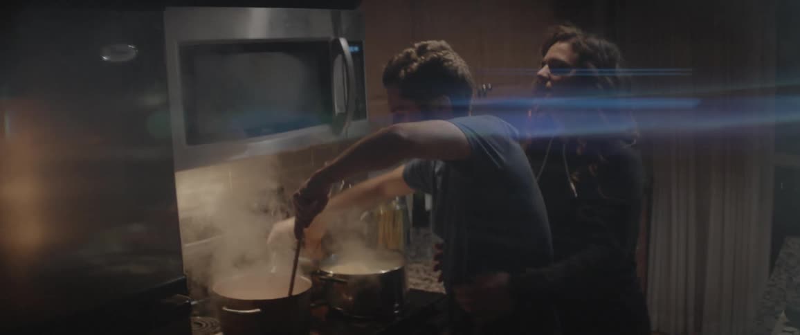 Man and woman rush to stir a smoking pot of food on the stove