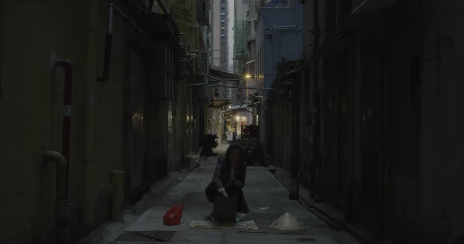 A woman is lighting someone in a dark alley