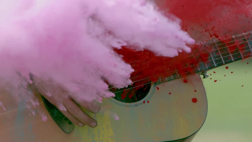 Powder exploding over a hand and acoustic guitar