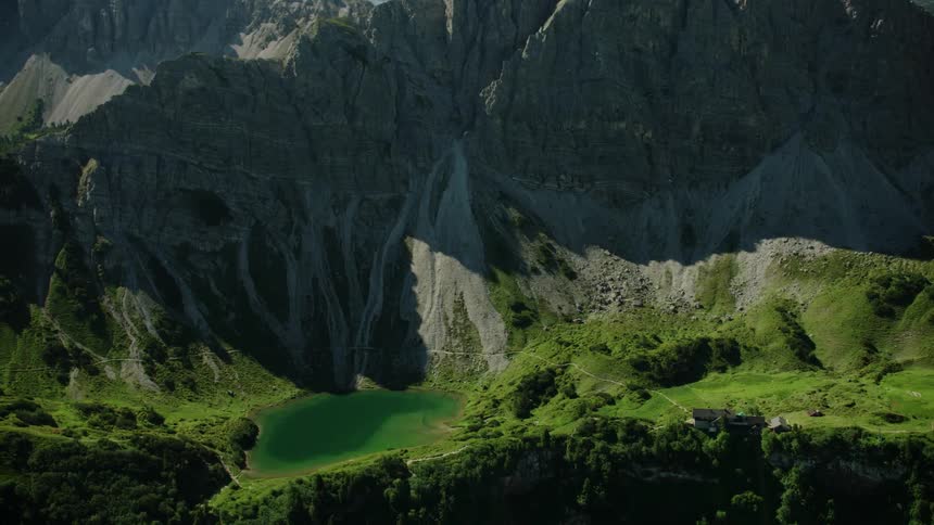 The tall mountains have green and water at the bottom