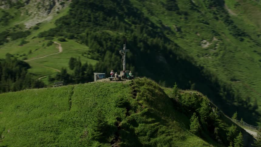People are standing by a cross on top of a mountain