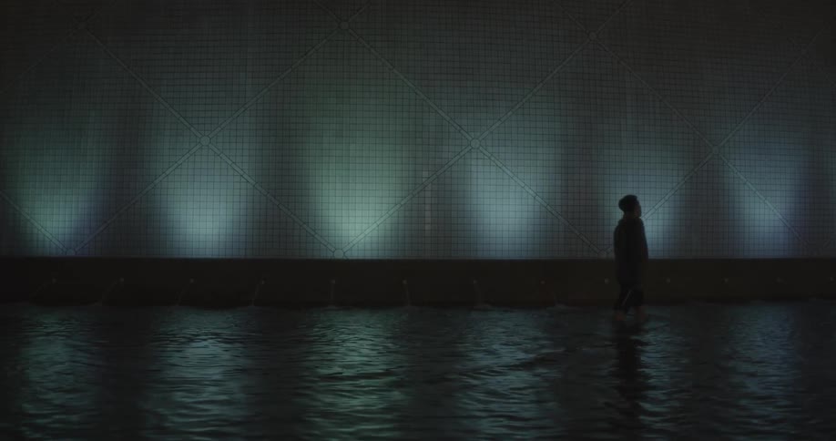 A man walks in the fountain water at night