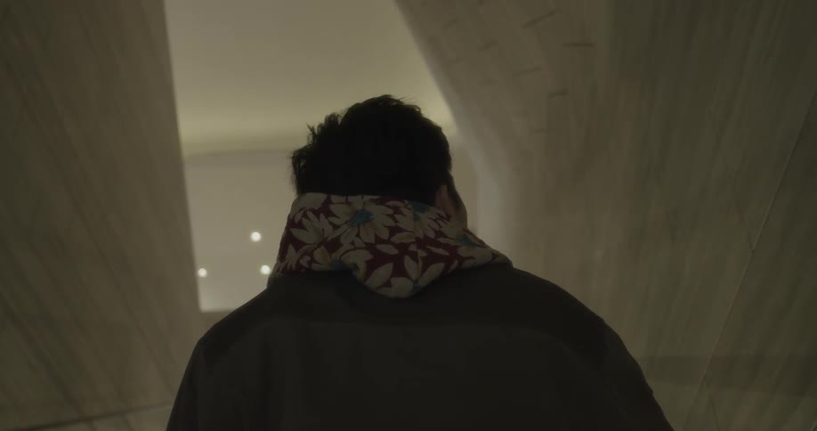 A man is riding an escalator up a dark hall