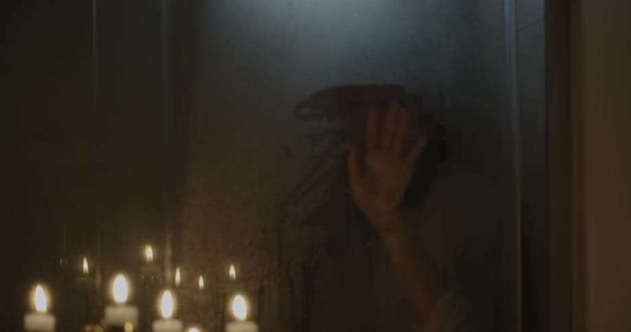 A woman wipes the moisture off the glass in the shower