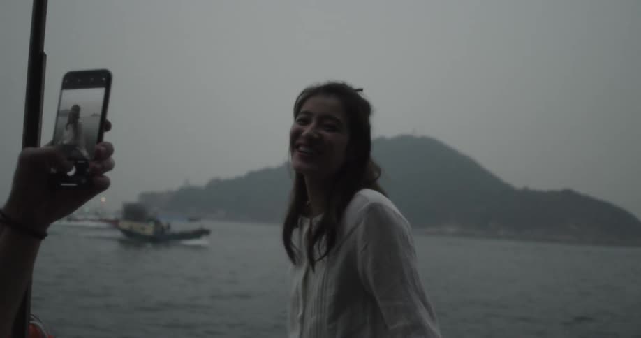 A woman poses for photographs by the water