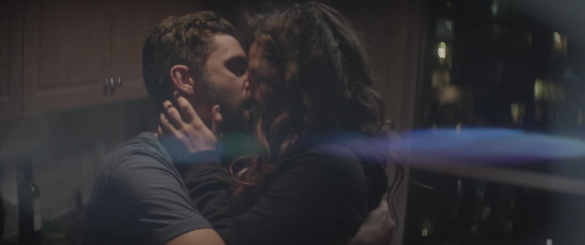 A couple kiss in a kitchen