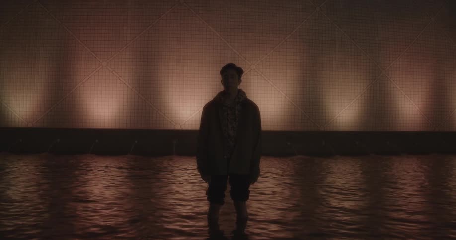 A man is standing in the water at night