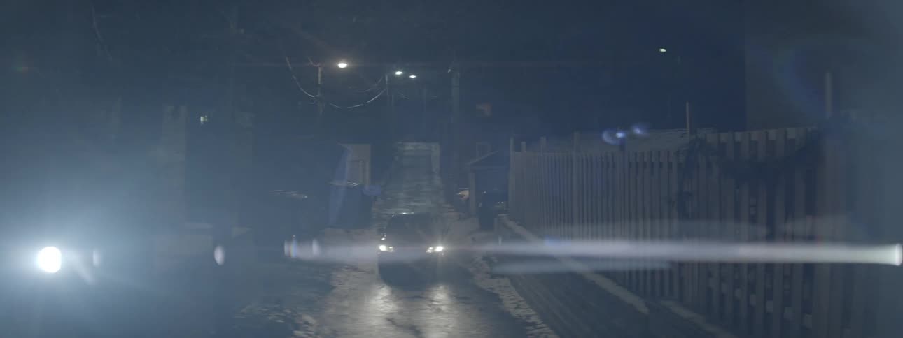A person walks past a parked car at night