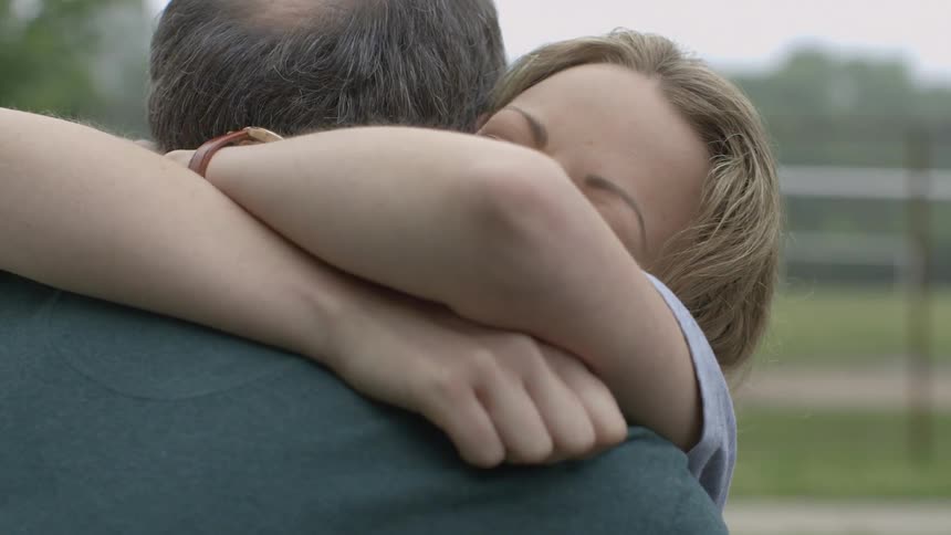 A woman smiles and hugs a man on the field