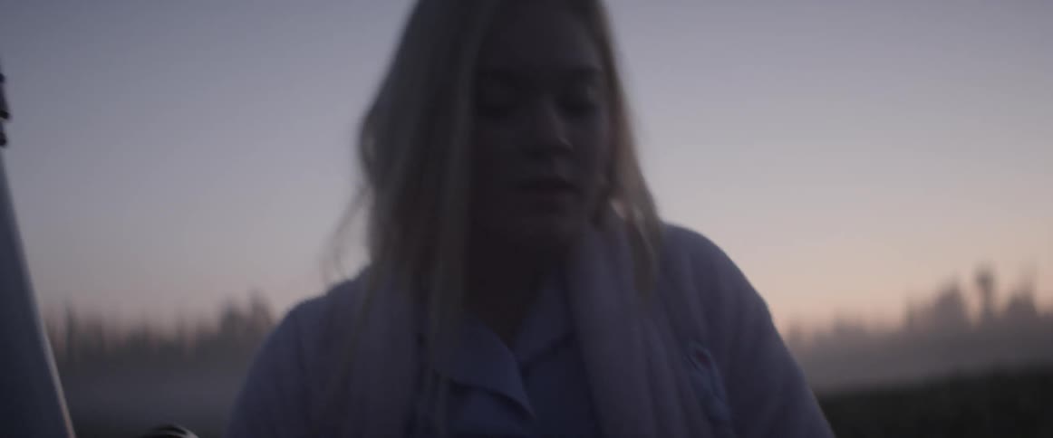 Woman in robe carrying telescope outside after sunset