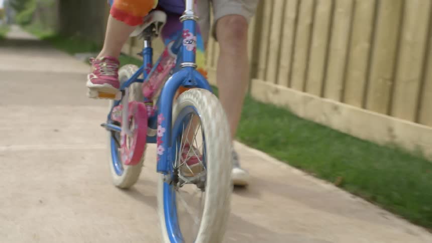 A man is helping a child learn to ride a bicycle