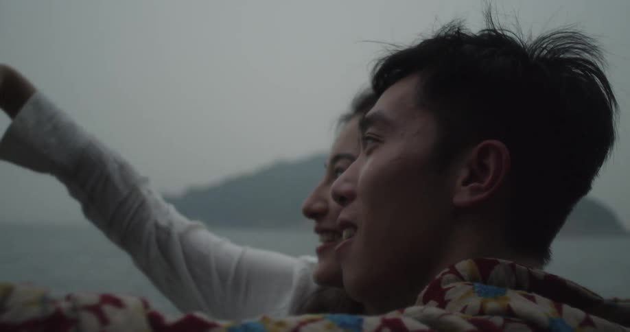 A man and woman take photographs of themselves by the water