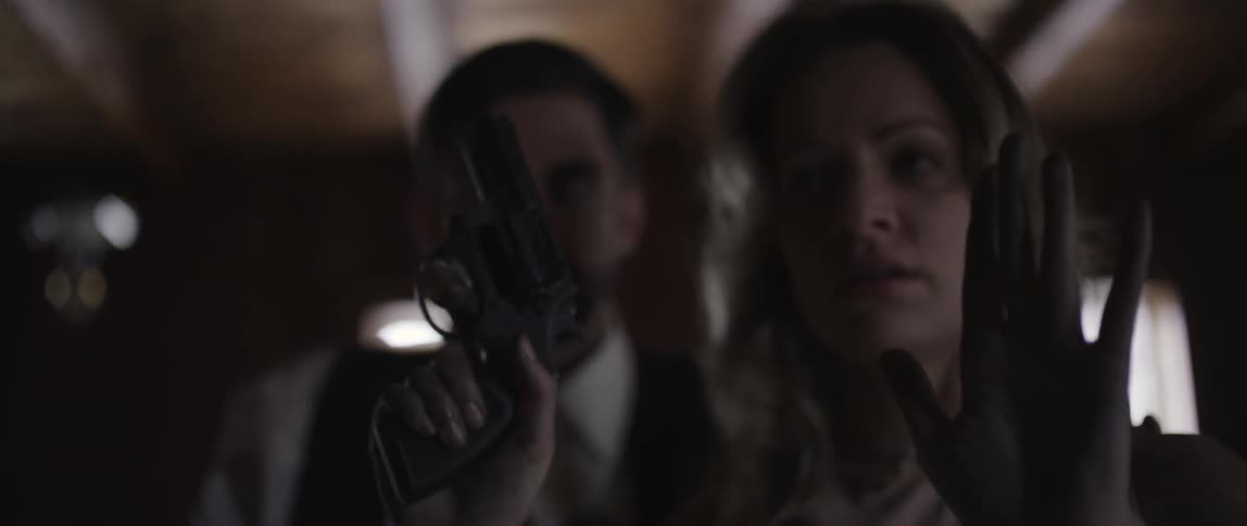 A woman aims a handgun and then lowers it in surrender