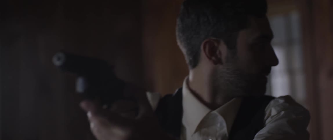 A man holding a gun looks around a room