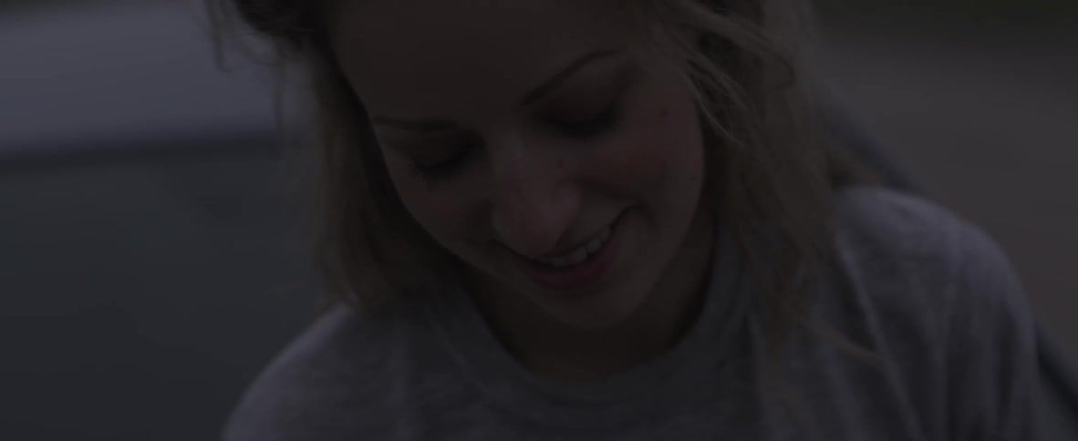 A woman is leaning forward smiling in the dark