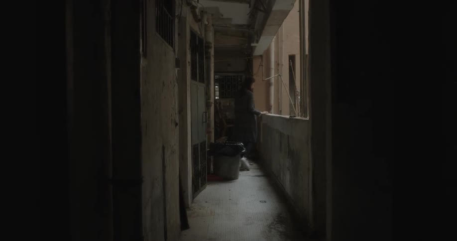 A woman walks down the hall and looks over the balcony before sitting