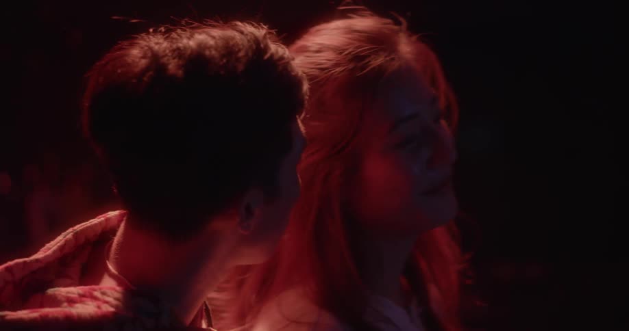 A man and woman talk under flashing lights