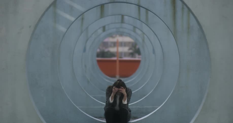 A woman walks through circular concrete structures and sits down