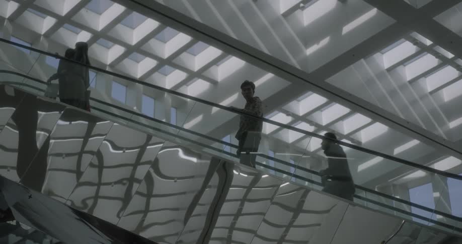 People walk and stand as they ride an escalator up