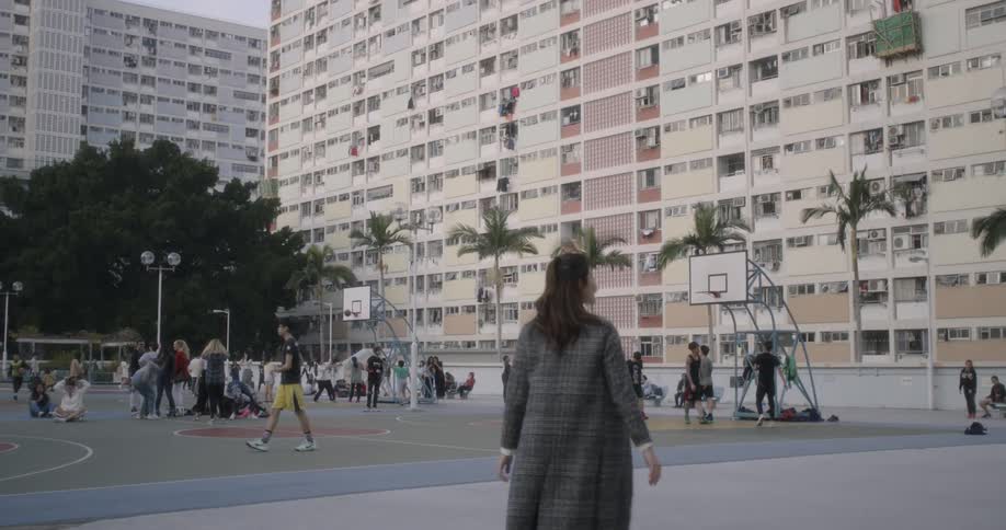 A woman walks onto a basketball court full of people