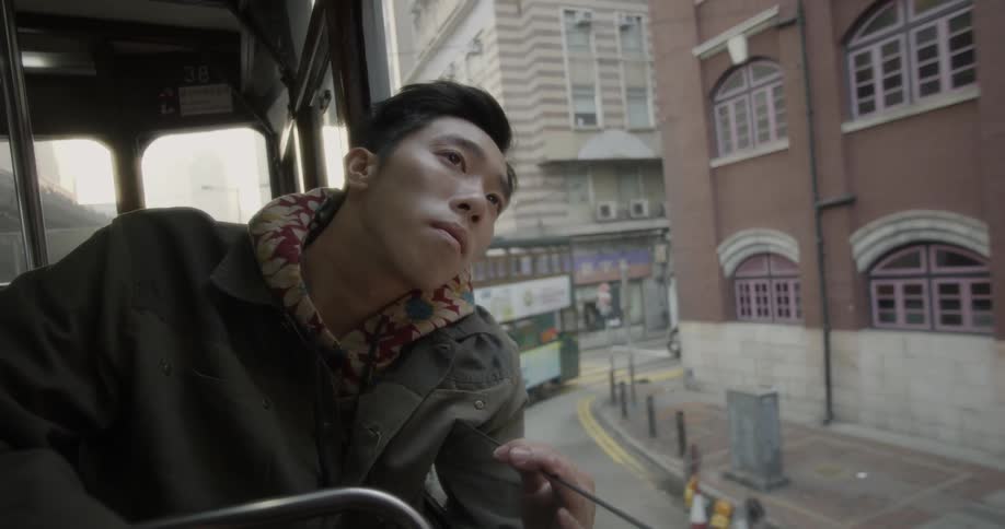 Man riding on top floor of tour bus in city