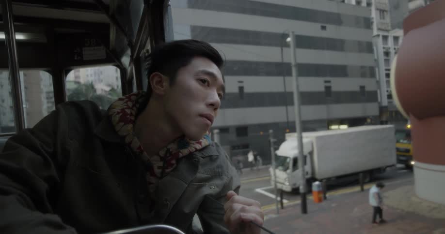 Man sight seeing while riding on top floor of tour bus in city