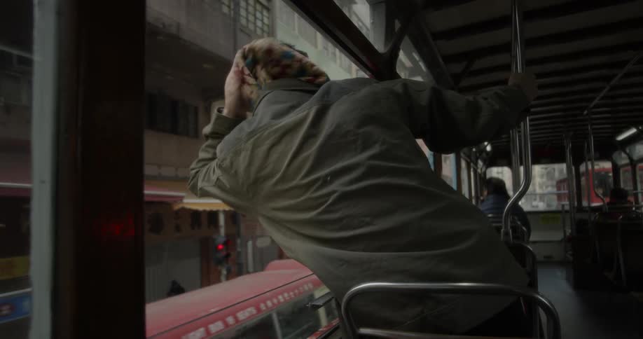 Man sight seeing while riding on top floor of tour bus in city