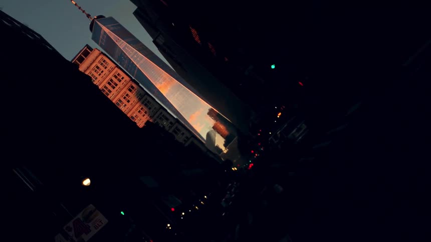 The sky and sunlight reflect on a skyscraper at the end of a city street