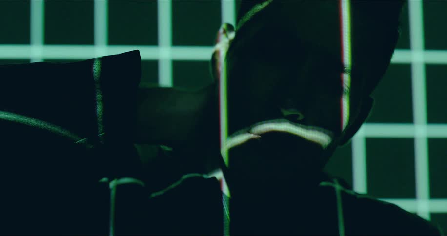 A man is in the dark rubbing his neck as lights flash