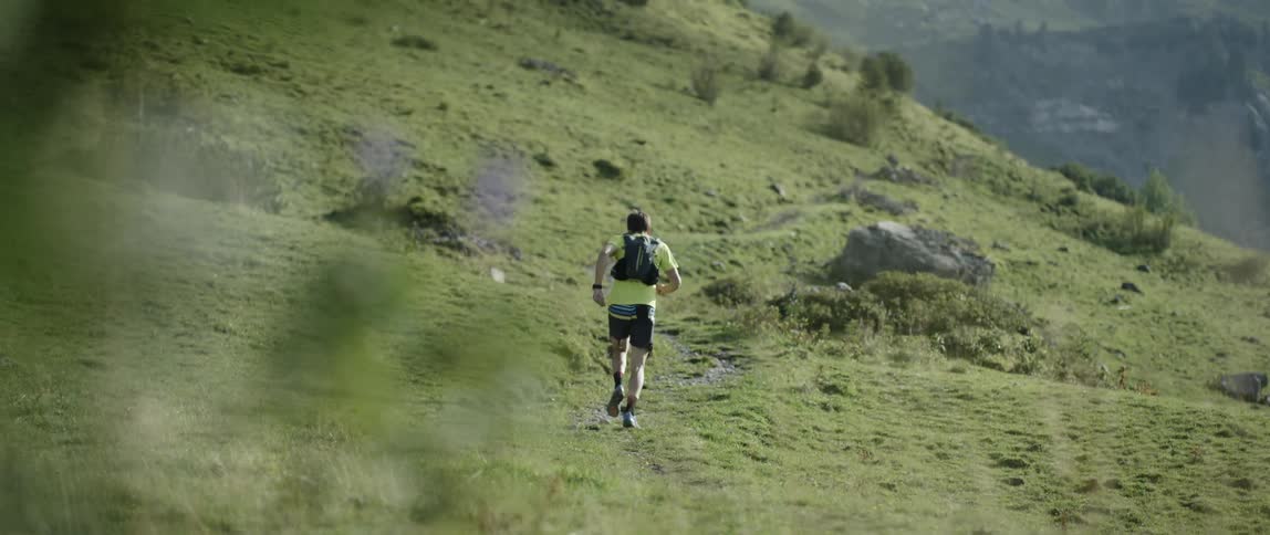 A man runs past grass up a hill