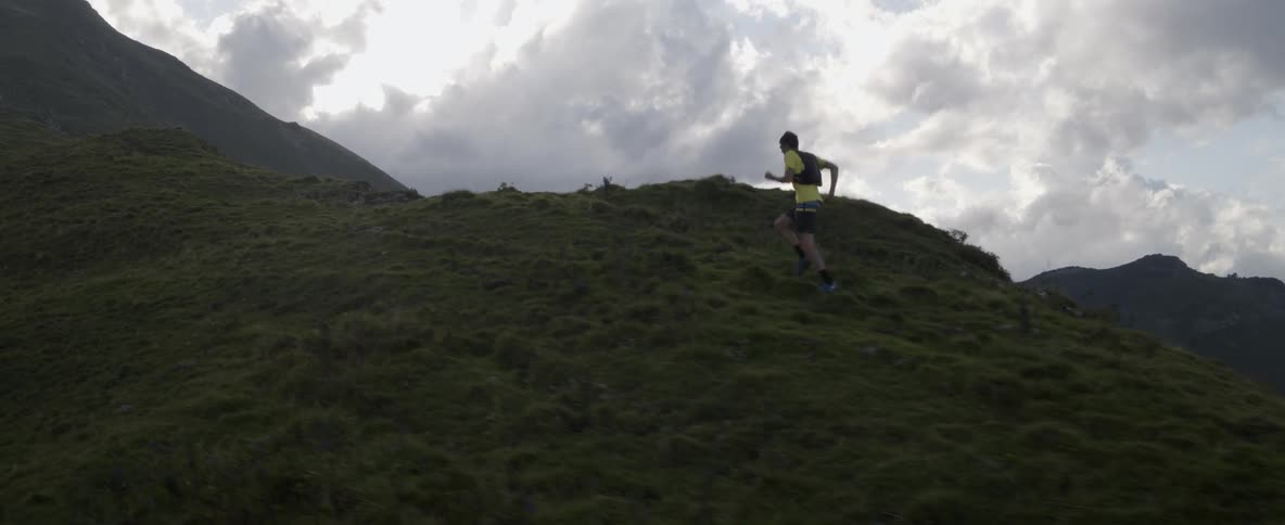 A man is jogging up a steep hill on a cloudy day
