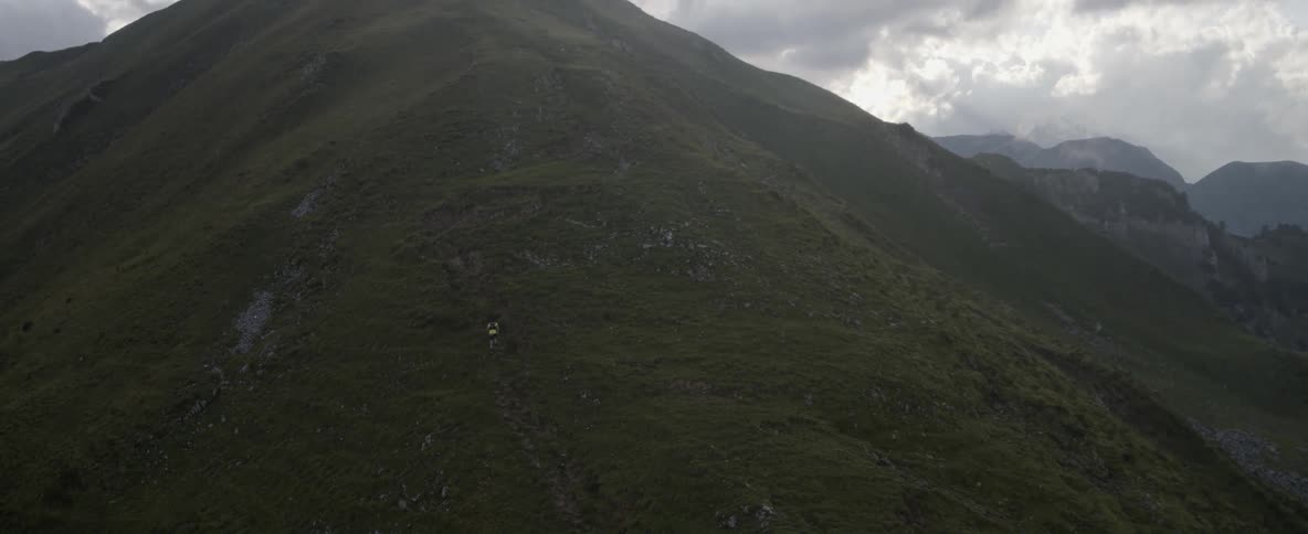 Person hikes up a tall grassy mountain