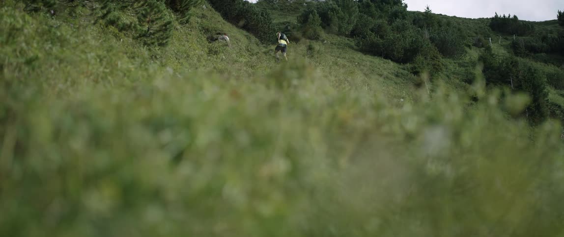 A man runs up a grassy mountainside