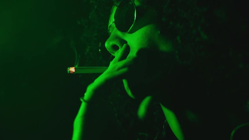 A woman with sunglasses has a smoke