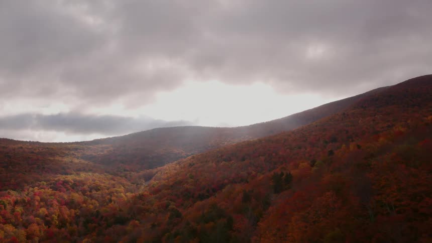 The sun is starting to shine through the clouds over the mountains in the distance
