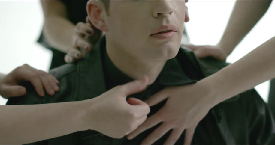 A man wearing black has his head and shoulders rubbed by multiple women