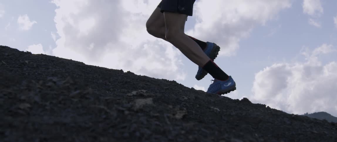 A man runs uphill jumping over the rocks