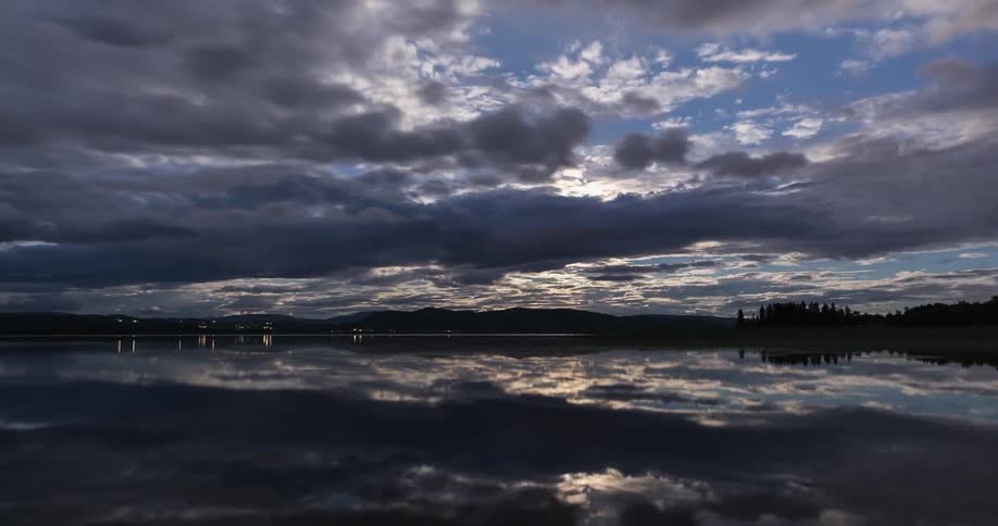 A calm lake on a cloudy moonlit sky