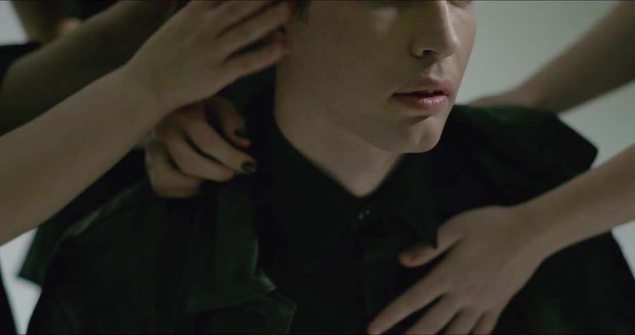 A man's face and hair are caressed by several hands