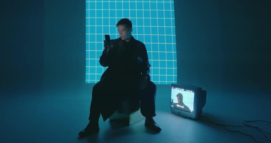 A man looks at his phone with a television on the ground