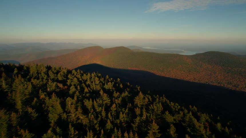 The sun shines on mountain forests and peaks