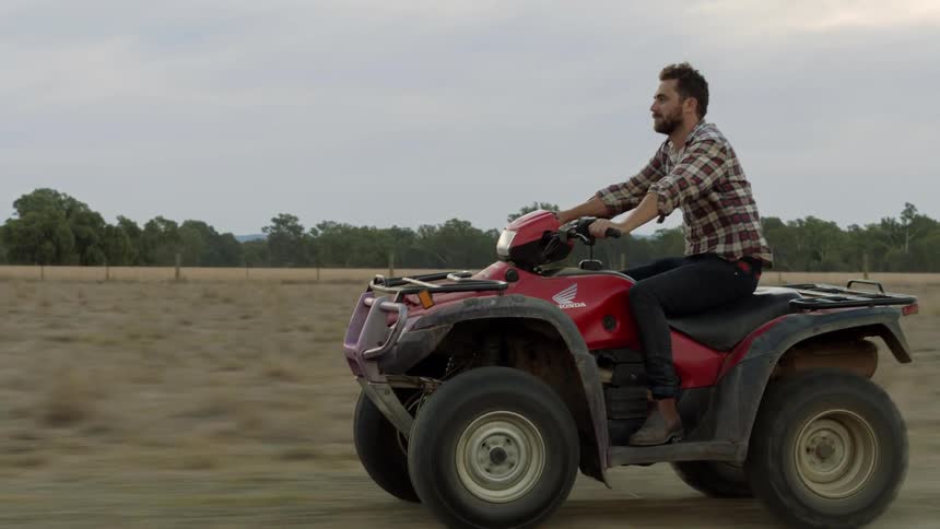 A man rides a four wheeler on a cloudy day